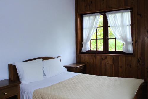 ein Schlafzimmer mit einem weißen Bett und einem Fenster in der Unterkunft Casa do Cadaval in Rio Caldo