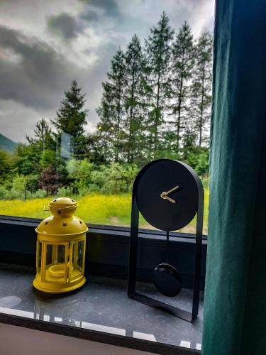 a clock and a chair sitting in a window at Domek Veron in Wysowa-Zdrój