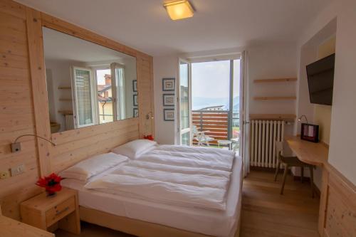 Hotel Miralago في Bossico: غرفة نوم بسرير ابيض ونافذة كبيرة