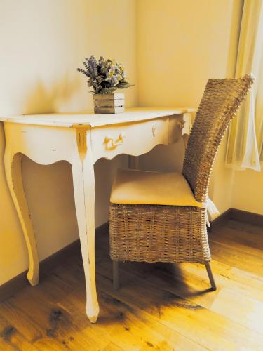 a desk with a wicker chair and a table with flowers at Il posto al sole in Teglio
