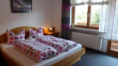 1 dormitorio con cama con almohadas y ventana en Ferienwohnung Allgäuer Landhaus Stocker in Hopferau-Füssen, en Hopferau