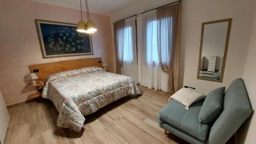 ein Schlafzimmer mit einem Bett, einem Stuhl und einem Spiegel in der Unterkunft CASA ROBY in Follina