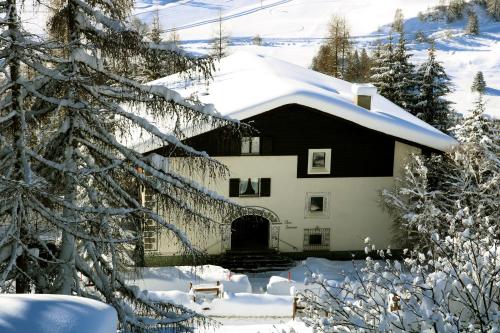 une maison avec de la neige sur le toit dans l'établissement Chesa Dominium, à Bergün