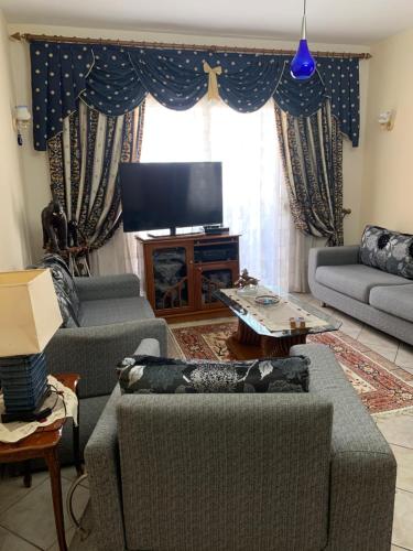 a living room with couches and a flat screen tv at Christina's house with 2 bedrooms and free parking in Gjirokastër