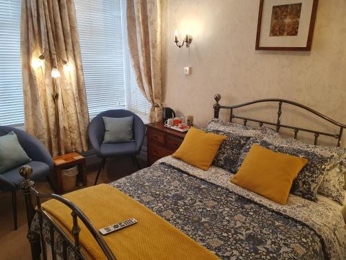 a bedroom with a bed with yellow pillows and two chairs at St Michael's Boutique Guest House B&B in Scarborough