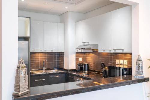 uma cozinha com armários brancos e um balcão preto em Prime Stylish Studio with Marina Views no Dubai