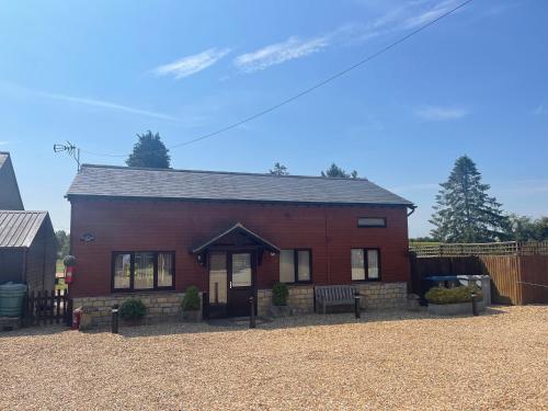 a red house with a bench in front of it at Kenns Farm - 2 Beautiful Barns in Carterton