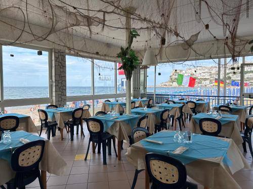 a restaurant with blue tables and chairs and the ocean at Villa Ialillo in Peschici