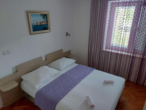 a bedroom with a bed with a window and a pillow at Apartment AB Batala in Dubrovnik