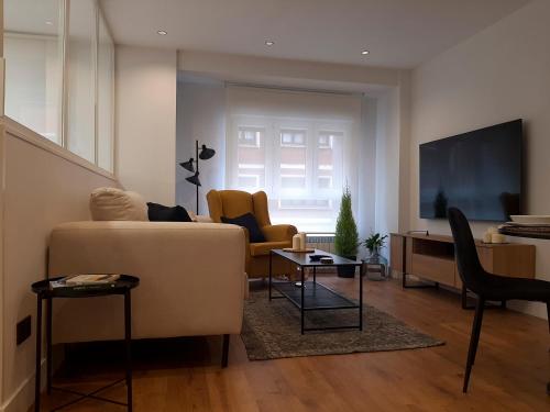 a living room with a couch and a tv at Apartamento Nordeste in Gijón