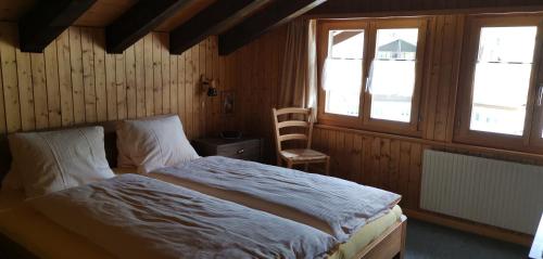 een slaapkamer met een bed en 2 ramen bij B&B Pension Lärch in Obergesteln