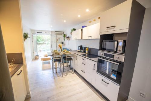 une cuisine avec des armoires blanches et une table avec des chaises dans l'établissement NEW Le Cocon-Clim-Vidéoprojecteur-Parking-Wifi-TOP PROS Conciergerie Montpellier, à Montpellier