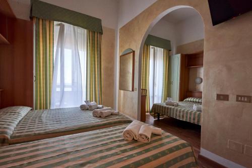 a bedroom with two beds with towels on them at Hotel Adriatica sul Mare in Rimini