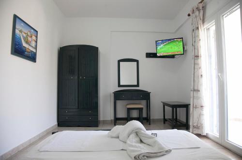 1 dormitorio con 1 cama y TV en la pared en Ο Μήλας en Agios Dimitrios