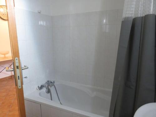 a bathroom with a bath tub with a shower curtain at Studio en rez de chaussée, avec jardin partagé. in Vars