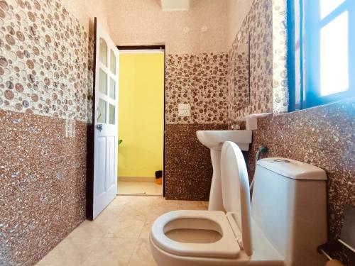 a bathroom with a toilet and a yellow door at Partners Shimla in Shimla