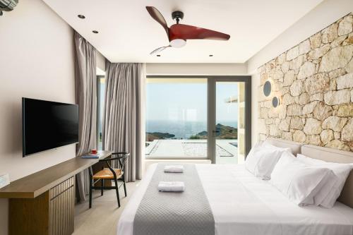Villa 7 Seas - With Amazing View في Lefkogeia: غرفه فندقيه سرير كبير وتلفزيون