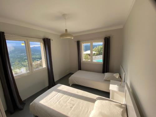 une chambre avec deux lits et deux fenêtres dans l'établissement villa du Passeron, à Chambonas