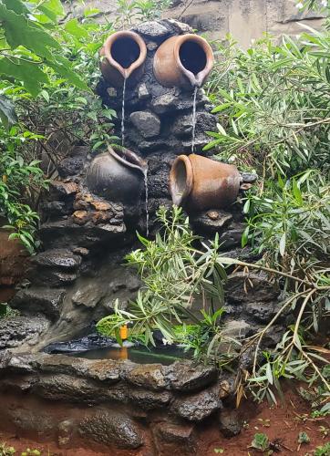 a water feature in a garden with three pots at Edaala Comfort - B&B in Nairobi
