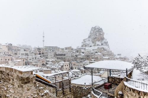 a city covered in snow with a mountain in the background at Hezen Cave Hotel in Ortahisar