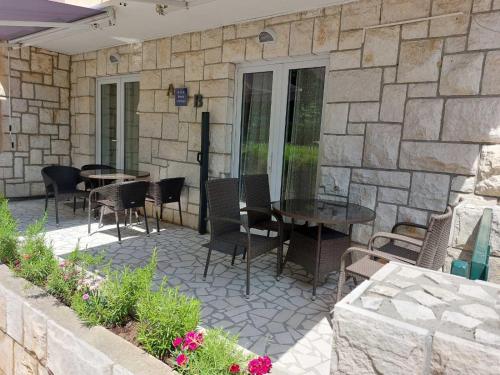 un patio con sillas, mesas y una pared de piedra. en Apartment AB Batala, en Dubrovnik