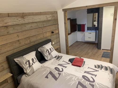 ein Schlafzimmer mit einem Bett mit einer Holzwand in der Unterkunft Chambre d'hôtes NATURISTE Le Jardin Des Hirondelles in Blanzaguet-Saint-Cybard