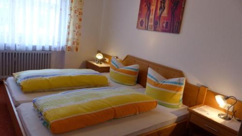 una camera con 2 letti con cuscini gialli e blu di Allgaeuer-Landhaus-Stocker a Hopferau