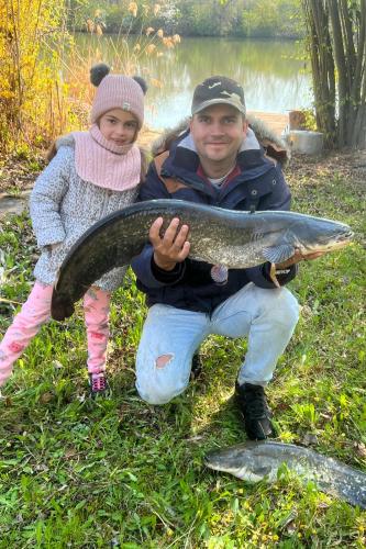 a man and a little girl holding a fish at Villa Popeye Jakuzzis nyaralóház in Békésszentandrás