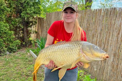 a woman holding a large fish in her hands at Villa Popeye Jakuzzis nyaralóház in Békésszentandrás