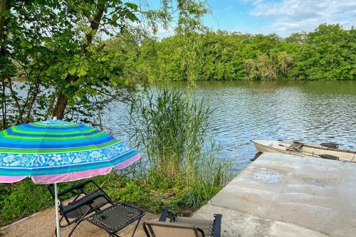a table and chairs with an umbrella next to a lake at Villa Popeye Jakuzzis nyaralóház in Békésszentandrás