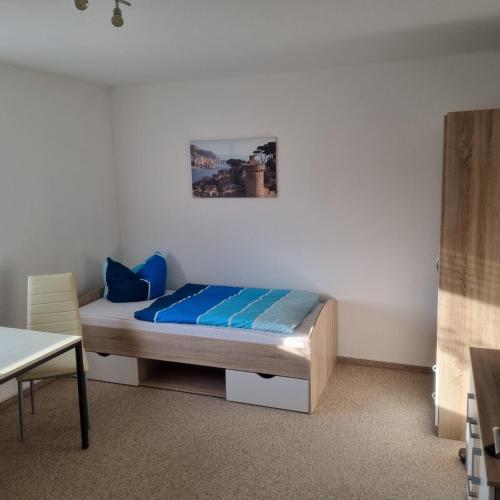 a bedroom with a bed with blue sheets and a picture on the wall at Appartmenthaus Zum Goldstern Monteurswohnung in Staßfurt