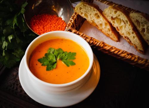 a bowl of soup on a plate with a basket of bread at Hezen Cave Hotel in Ortahisar