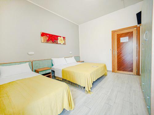 a hotel room with two beds and a door at Hotel Rio Beach & Breakfast in Cesenatico