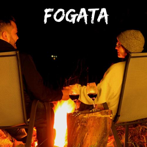a man and a woman sitting around a fire with wine glasses at Glamping Caliza La Calera in La Calera