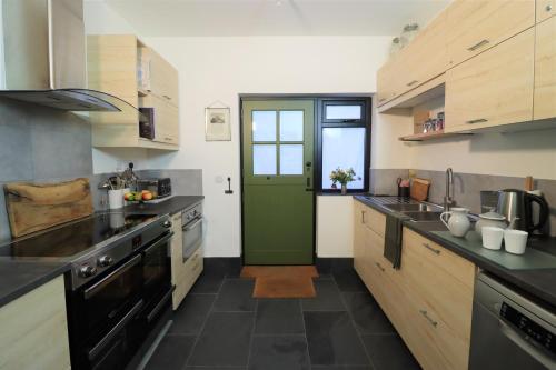 a large kitchen with a green door in it at Pavilion in Llantwit Major