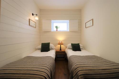 two twin beds in a room with a window at Pavilion in Llantwit Major