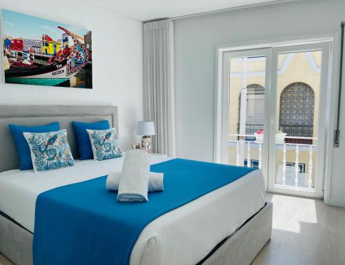 a bedroom with a blue and white bed with a window at Central Tiled Apartment in Aveiro