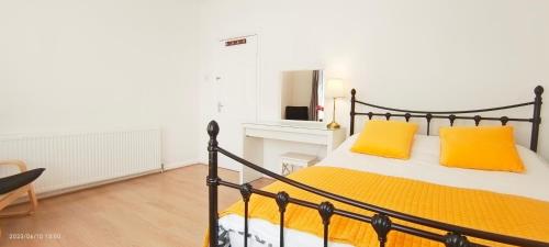 a bedroom with a bed with yellow pillows on it at Pearl Garden in Wembley in London