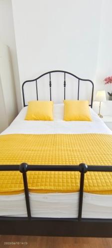 a bed with yellow pillows on it in a room at Pearl Garden in Wembley in London