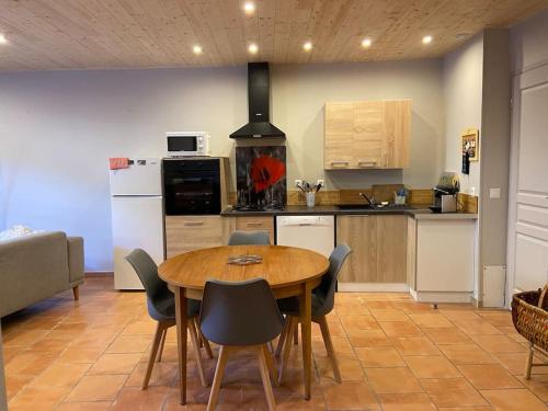 La cuisine est équipée d'une table, de chaises et d'un réfrigérateur. dans l'établissement Le petit Luxembourg, à Valleraugue