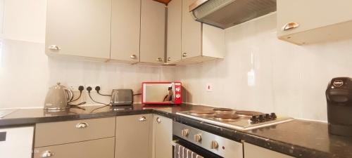 a kitchen with white cabinets and a red appliance at Pearl Garden in Wembley in London