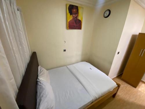 małe łóżko w pokoju z zegarem na ścianie w obiekcie Apartment D (Deluxe One Bedroom Apartment) w mieście Lagos