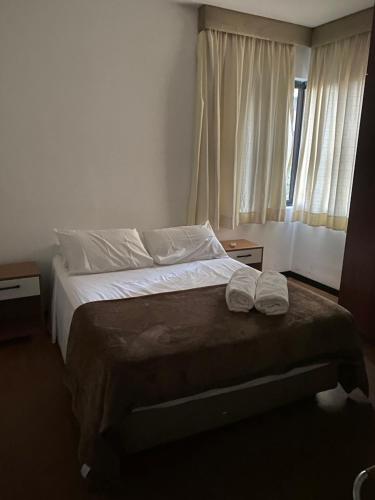 1 dormitorio con 1 cama con sábanas blancas y ventana en Apart Alameda Santos - Paulista, en São Paulo