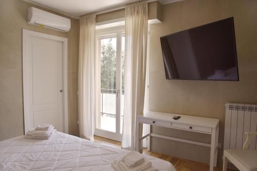 1 dormitorio con TV de pantalla plana en la pared en La Maison Latina Guest House, en Latina