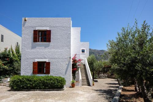a white house with red shutters and flowers on it at Eleftheria Studios in Balíon