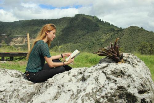 a woman sitting on a rock reading a book at Glamping Caliza La Calera in La Calera