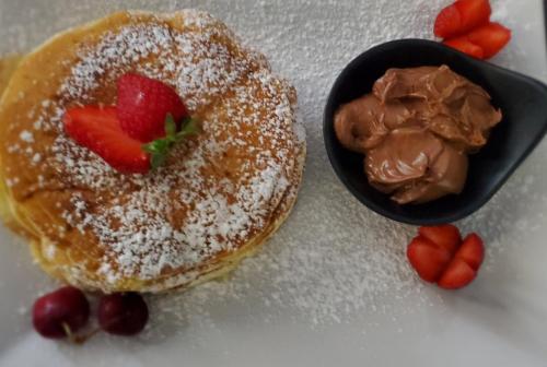 a pastry with powdered sugar and a bowl of chocolate at Villa Kristiano 21 in Sarandë