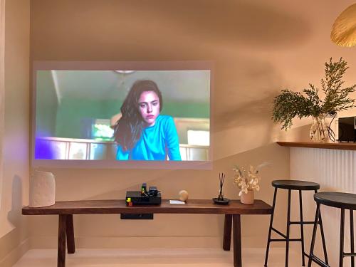 un écran de télévision sur un mur avec une table en bois dans l'établissement WELCOMING, LOVELY, CALM & CENTRALLY LOCATED FLAT, à Dijon