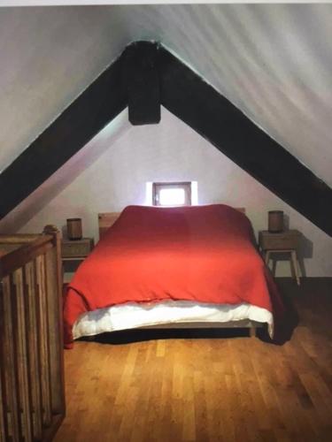 a bedroom with a red bed in an attic at La maisonnette des champs in Pierre-Buffière