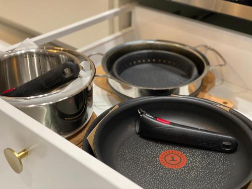 - 2 casseroles et poêles assises sur une cuisinière dans la cuisine dans l'établissement WELCOMING, LOVELY, CALM & CENTRALLY LOCATED FLAT, à Dijon